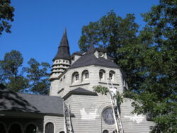 View of church from parking lot, clear sunny day, trees in background.